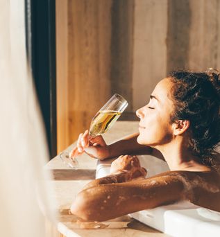 Eine Frau lehnt am Rand eines Whirlpools und genießt ein Glas Sekt
