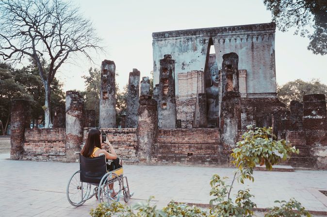Frau im Rollstuhl fotografiert ein Bauwerk