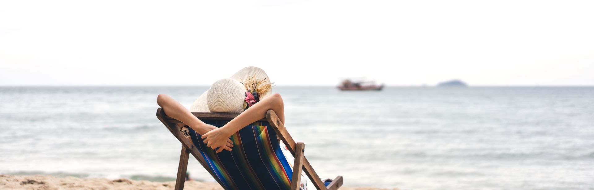 Person am Strand auf einer Liege schaut auf das Meer