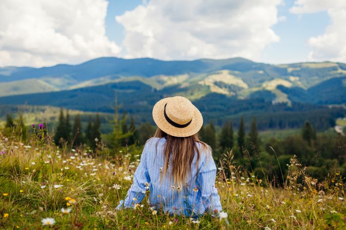 Frau liegt im Gras umgeben von einer Berglandschaft