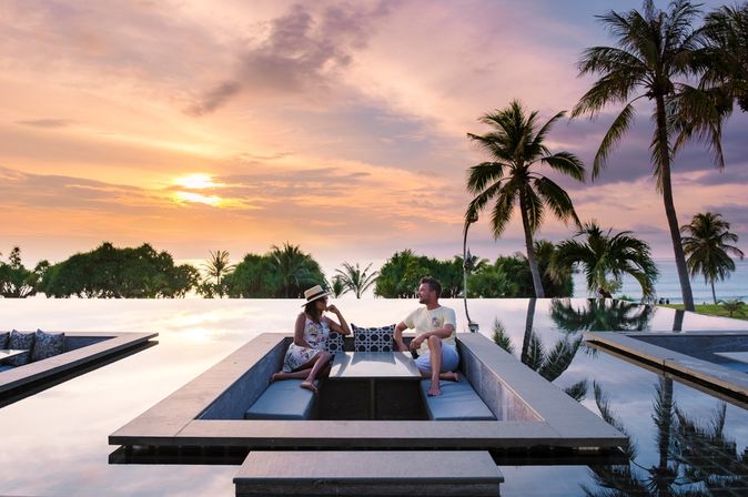 Ein Mann und eine Frau sitzen bei Sonnenuntergang in einer trockenen Sitzecke, die sich in einem Pool befindet
