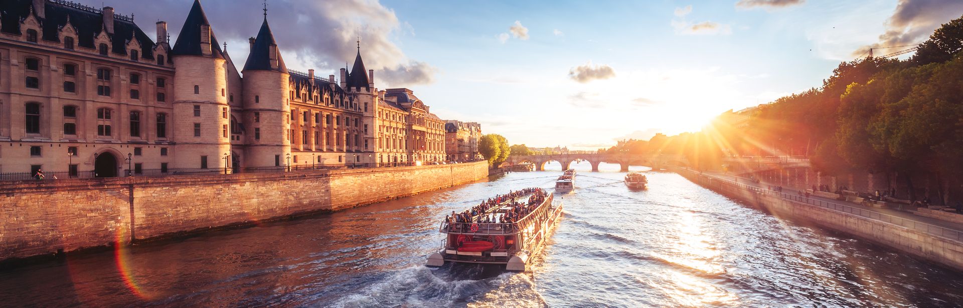 Flusskreuzfahrschiffe fahren an einer Burg entlang bei Sonnenuntergang