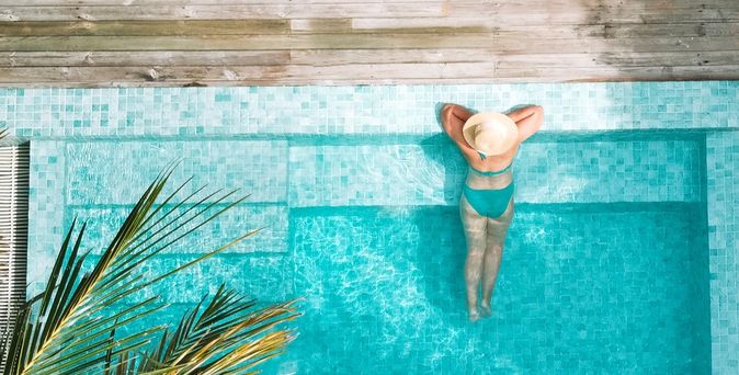 Eine Frau lehnt am Rand eines eleganten Pools