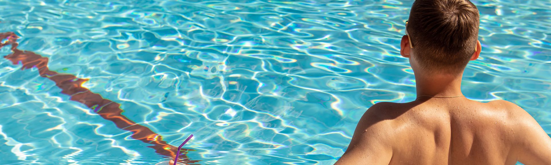 Mann mit Getränk in der Hand sitzt im Pool