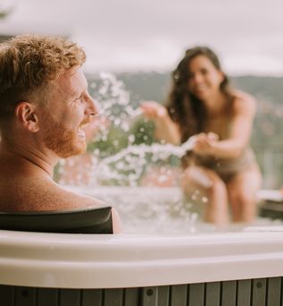 Zwei Personen im Whirlpool, die Frau macht den lachenden Mann nass