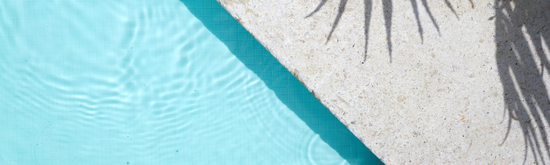 Pool von oben, auf dem Rand sieht man den Schatten einer Palme