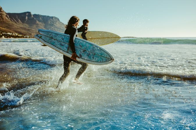 Surfer laufen auf das Meer zu