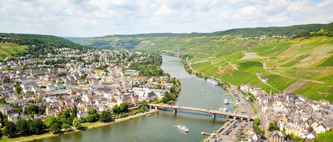 Fluss mit Brücke, die zwei Seiten eines Dorfes inmitten einer grünen Landschaft verbindet