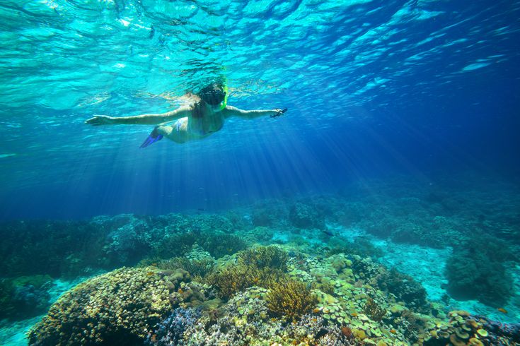 Ein Kind mit Schnorchel im Meer breitet die Arme aus