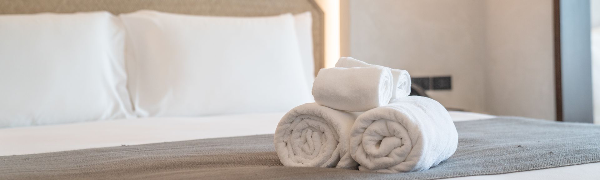 Aufgerollte Handtücher auf einem gemachten Bett