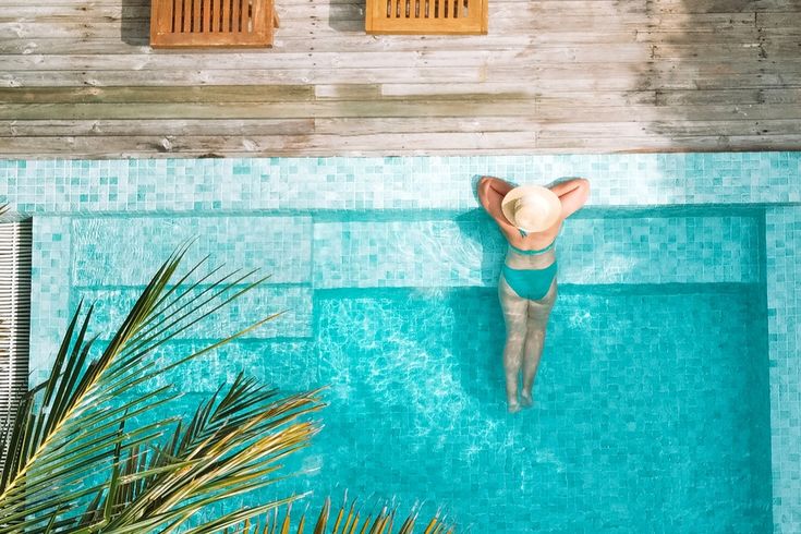 Eine Frau lehnt am Rand eines eleganten Pools