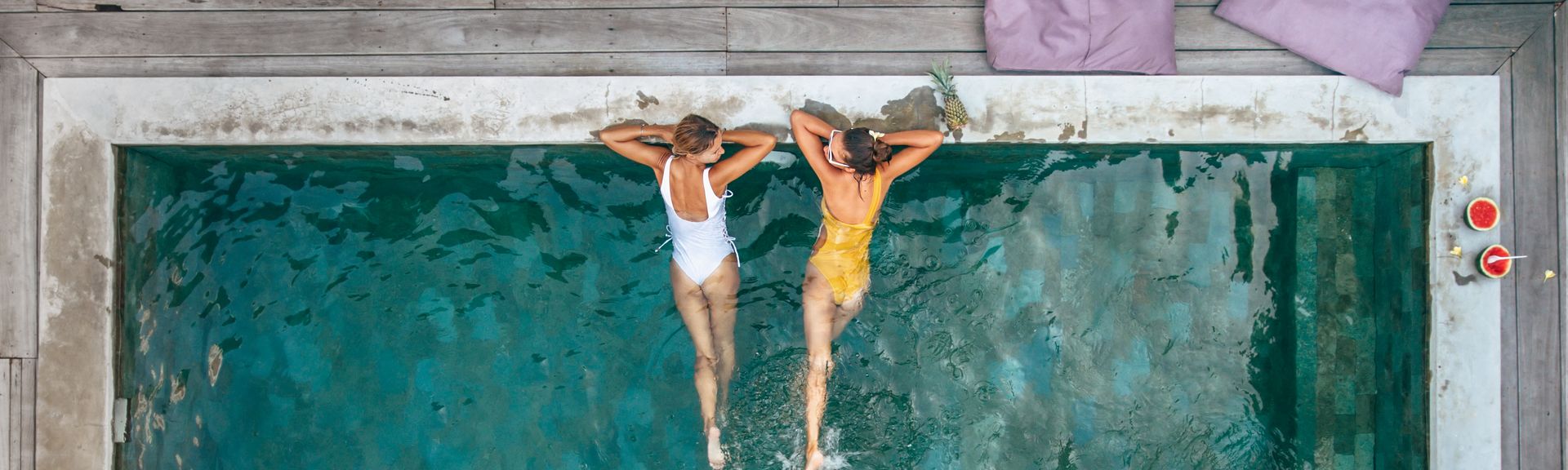 Zwei Frauen liegen im Pool und schauen sich an