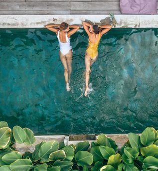 Zwei Frauen liegen im Pool und schauen sich an
