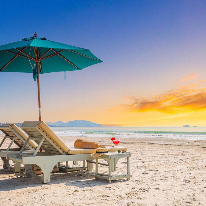 Zwei Liegen mit Sonnenschirm stehen am Strand