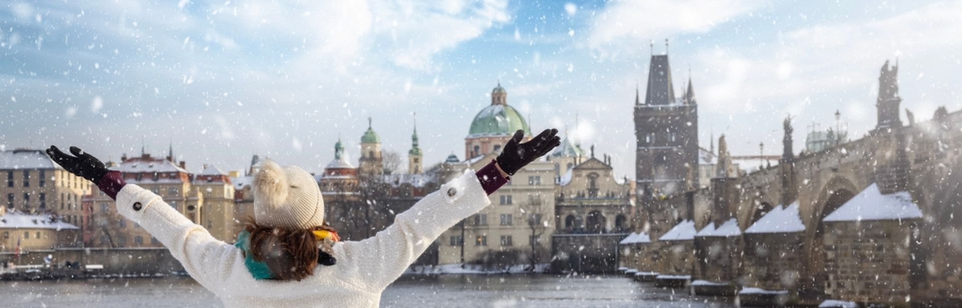Eine Frau steht vor einem Zaun an einem Fluss, der durch eine Stadt fließt, während es schneit