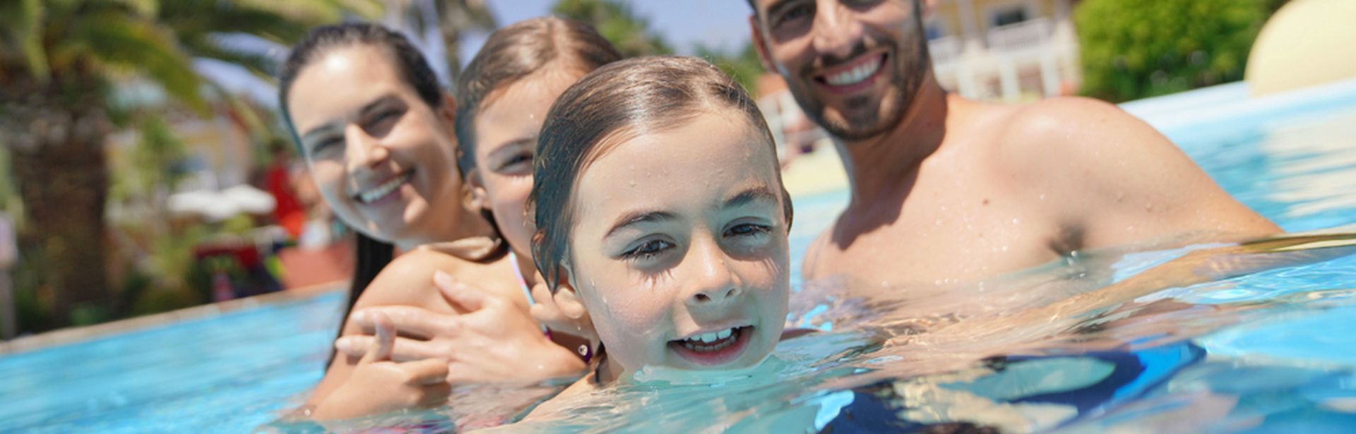 Eine Familie in einem Pool lächelt in die Kamera