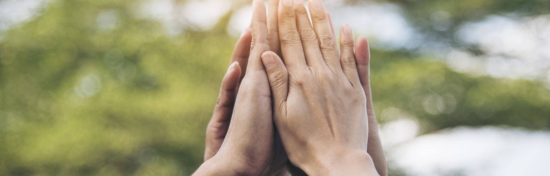 Ein Kreis aus Personen, wo jeder eine Hand in der Mitte in die Höhe zusammenhält. Zu sehen sind nur die Hände