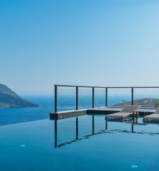 Infinity Pool mit zwei Liegen und dem Meer im Hintergrund