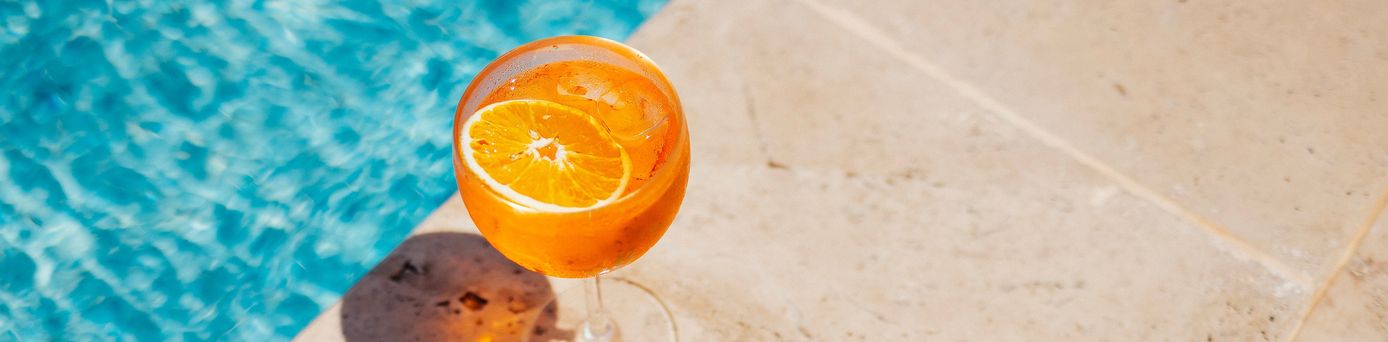 Ein Oranges Getränk steht am Rand eines Pools