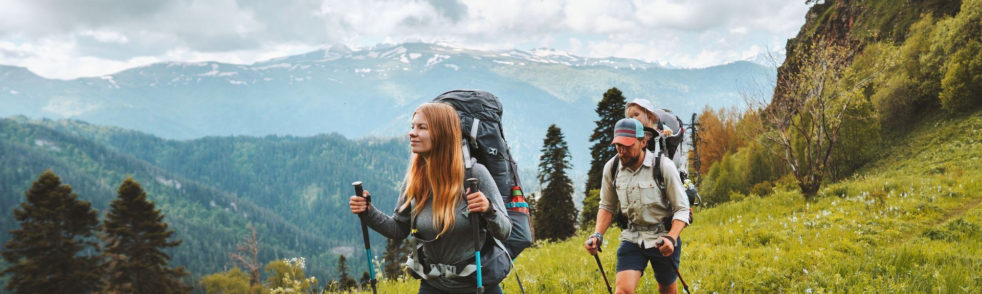 Zwei Personen wandern mit Nordic Walking Stöckern durch eine Wiese