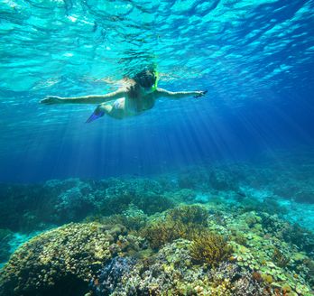 Ein Kind mit Schnorchel im Meer breitet die Arme aus