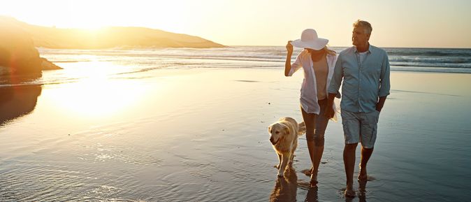 Ehepaar macht mit Ihrem Hund einen Spaziergang am Strand
