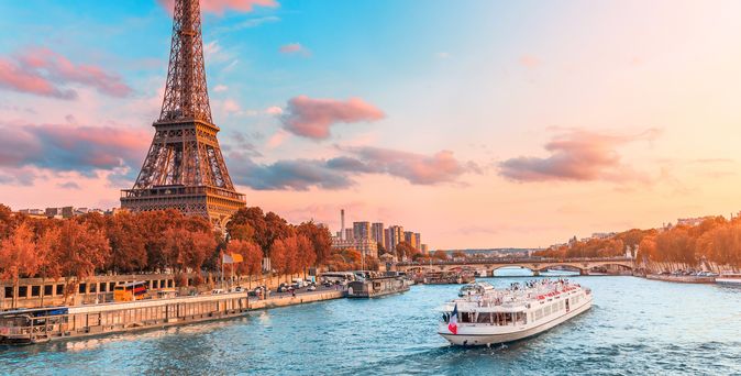 Flusskreuzfahrtschiff auf der Seine neben dem Eiffelturm in Paris