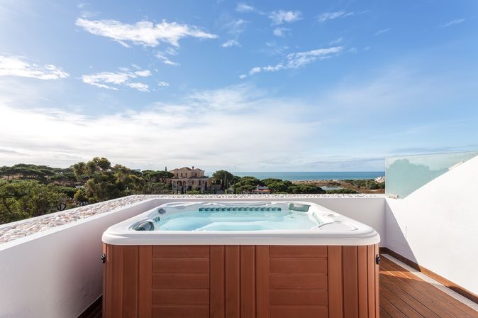 Ein Whirlpool auf einem Balkon mit weißer Brüstung bei Sonnenschein