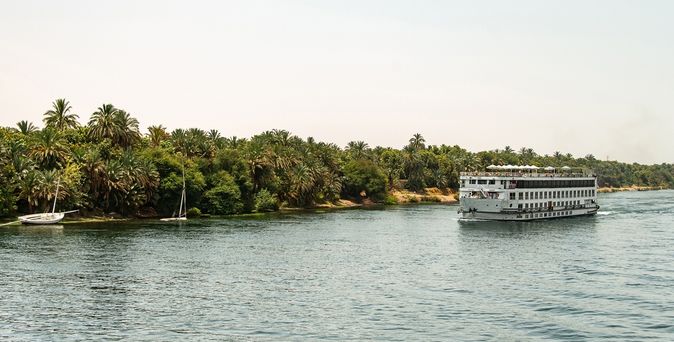 Flusskreuzfahrtschiff, mit Palmen im Hintergrud