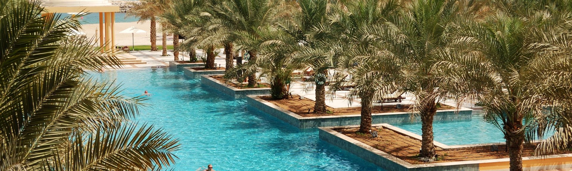 Poollandschaft mit Palmen und Blick auf das Meer