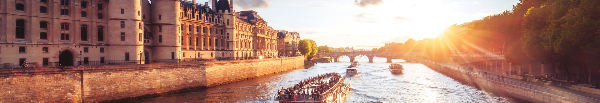 Flusskreuzfahrschiffe fahren an einer Burg entlang bei Sonnenuntergang