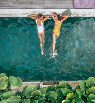 Zwei Frauen liegen im Pool und schauen sich an