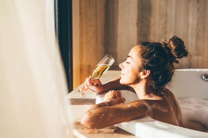 Eine Frau lehnt am Rand eines Whirlpools und genießt ein Glas Sekt