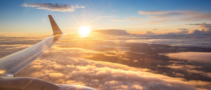 Sonnenuntergang über den Wolken aus einem Flugzeugfenster aus