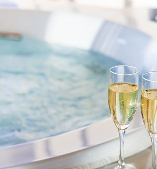 Zwei Sektgläser stehen am Rand eines Whirlpools