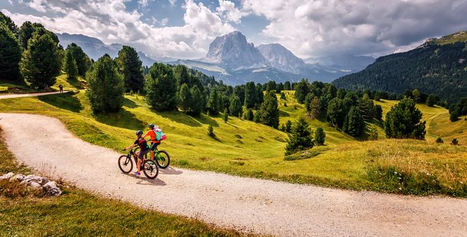 Zwei Personen fahren bei gutem Wetter Fahrrad durch eine Berglandschaft