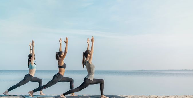 Drei Frauen machen Yoga am Strand