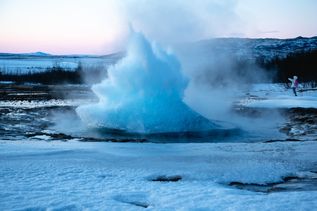 Ein ausbrechender Geysir in winterlicher Landschaft