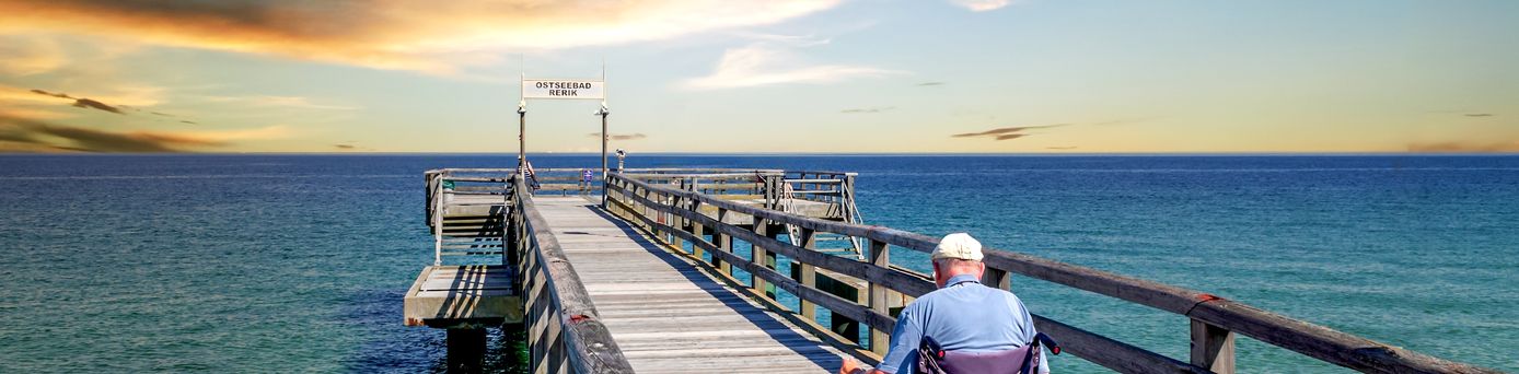 Mann im Rollstuhl auf einer Seebrücke am Meer