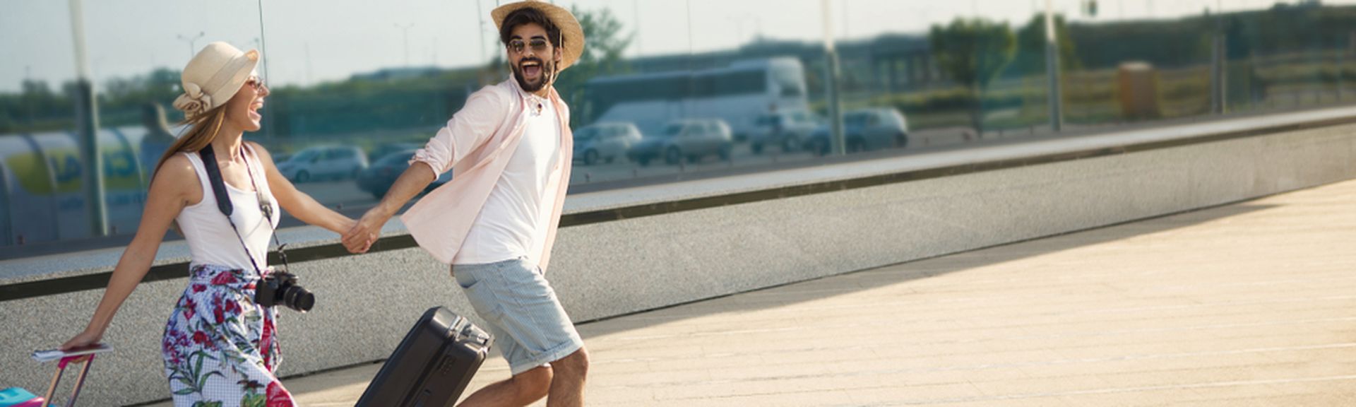 Ein Paar läuft mit Koffern aufgeregt einen Weg entlang