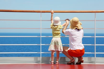 Mutter und Kind stehen an der Reling von einem Kreuzfahrtschiff und schauen auf das Meer