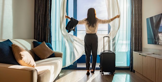 Eine Frau öffnet die Vorhänge ihres modernen Hotelzimmers