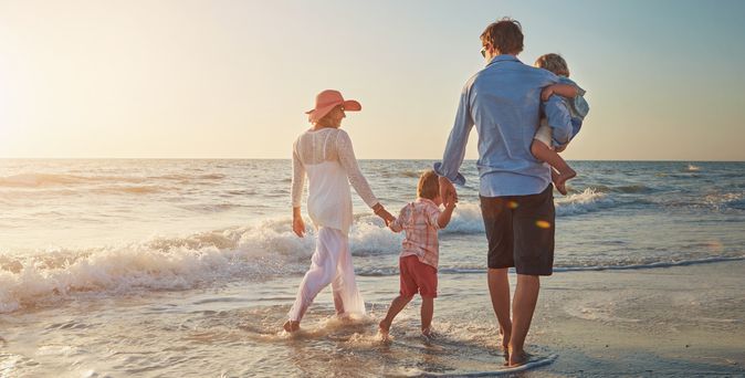 Familie, die einen Strandspaziergang beim Sonnenuntergang macht
