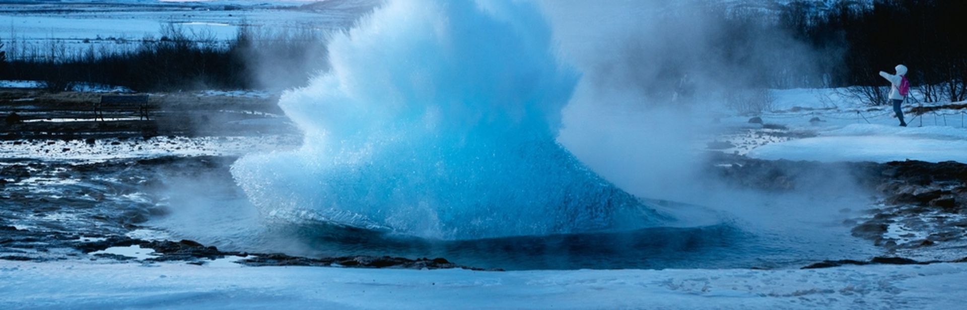 Ein ausbrechender Geysir in winterlicher Landschaft