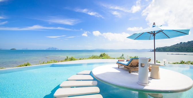 Ein Tisch mit kleinem Sonnenschirm und Getränken steht im Pool