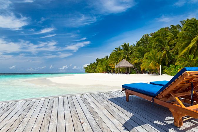 Zwei Liegen auf einer Terrasse mit Strandzugang