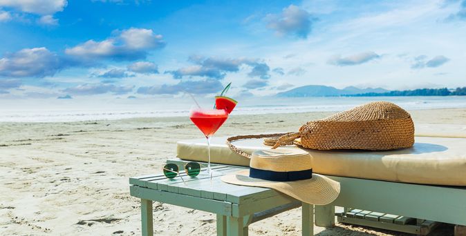 Eine Liege und ein Tisch mit einem Sonnenhut und einem Getränk am Strand