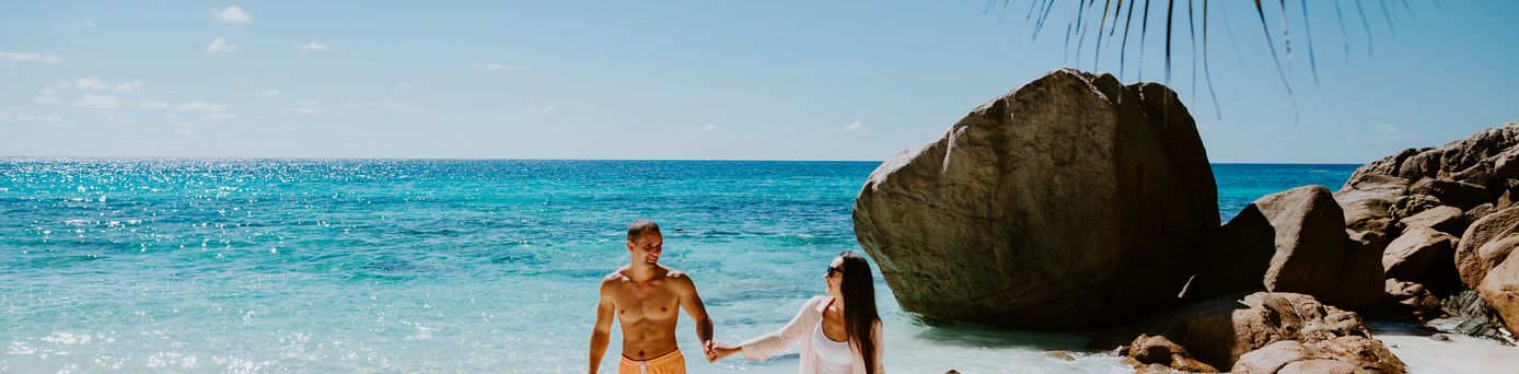 Paar läuft händchen haltend am Strand entlang