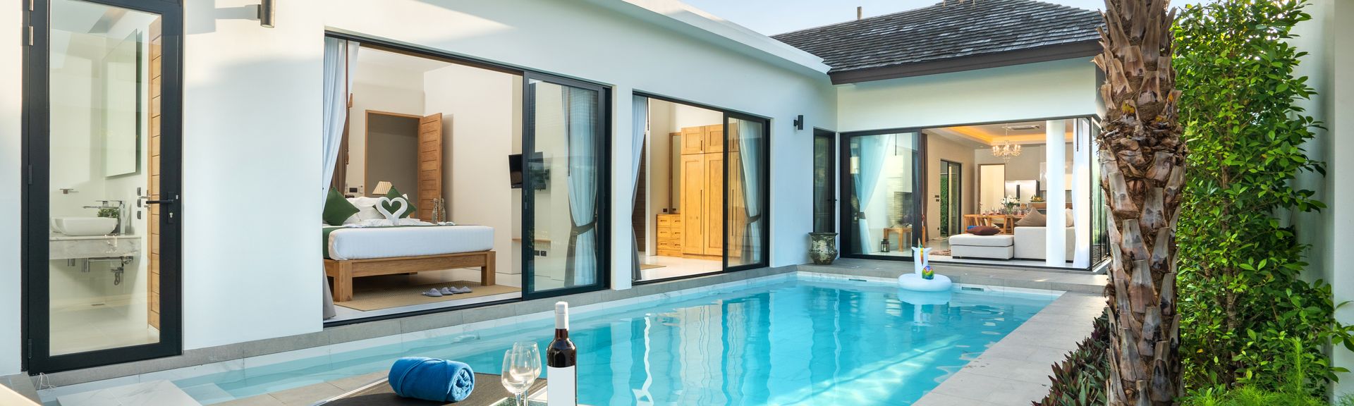 Ein Pool vor einer eleganten Villa mit zwei Liegen und einem Tisch