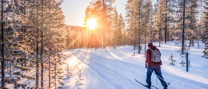 Mann auf Skiern läuft durch eine Schneelandschaft